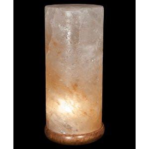 A cylindrical salt lamp made of natural translucent salt, glowing with a warm light from within, set against a solid black background.